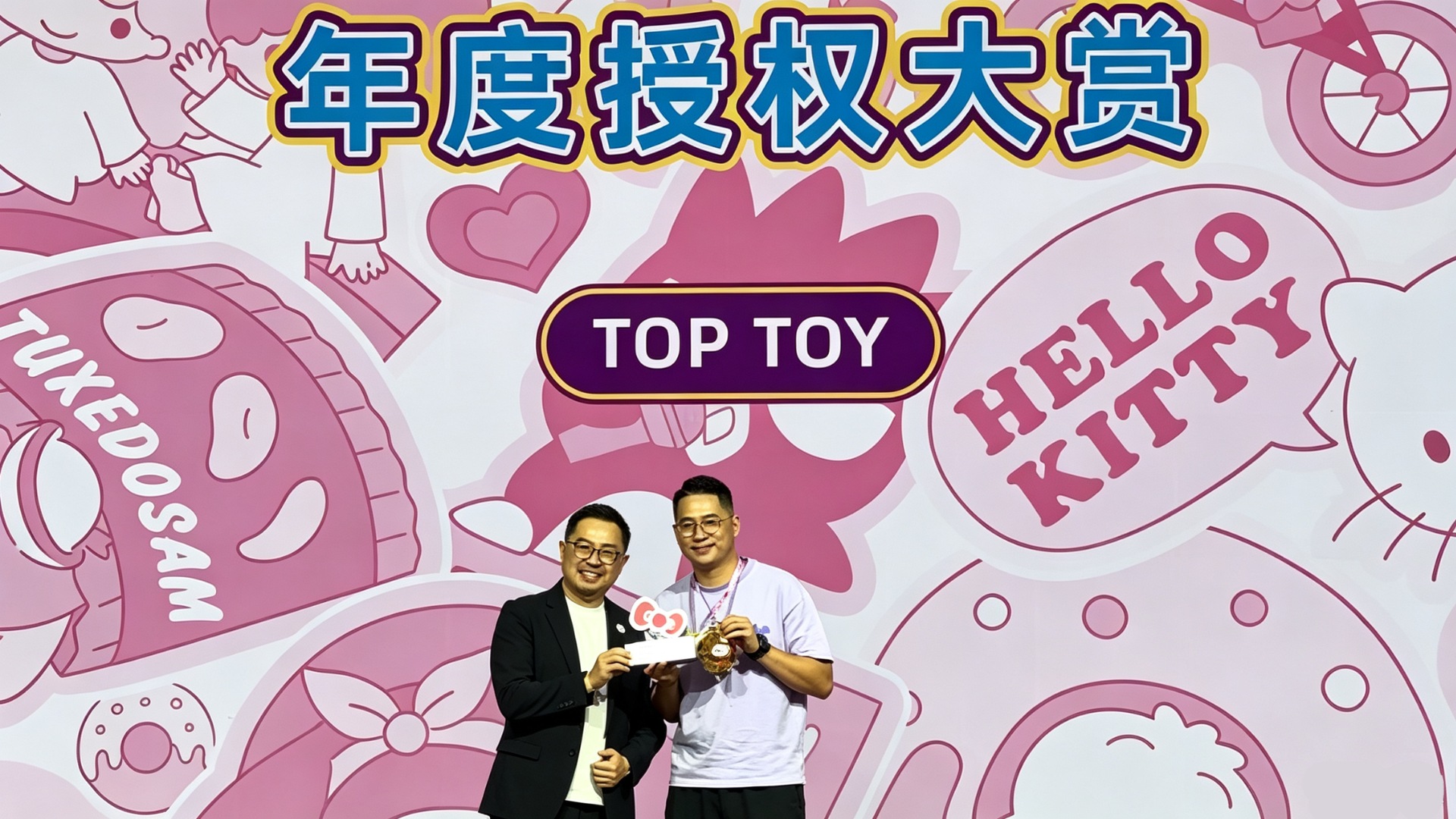 Award ceremony photo: Mr. Otsuka presents trophy to TOPTOY CEO Sun Yuanwen, backdrop printed with Annual Licensing Award title, TOPTOY logo and Sanrio character graphics