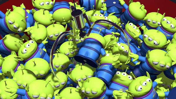 The Toy Story aliens standing together in their green spacesuits inside a claw machine